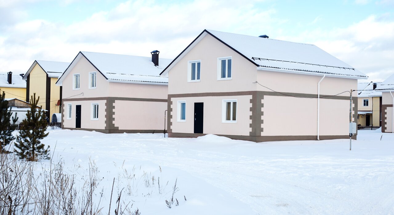 Energy-efficient homes in a snowy neighborhood featuring external wall insulation systems with a rendered finish, designed to retain heat, reduce energy bills, and improve winter comfort