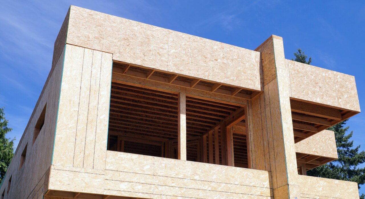 Timber frame building under construction with OSB sheathing, a common substrate for applying external wall insulation systems in new build properties