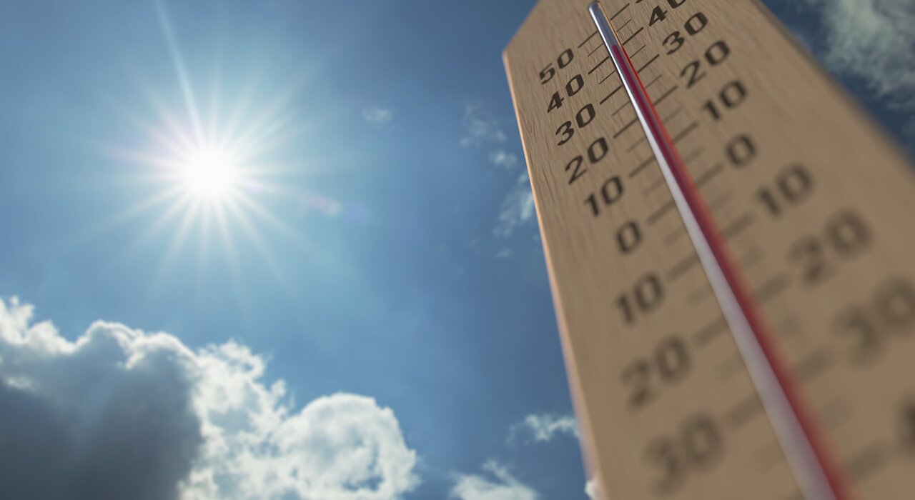 Thermometer rising under direct sunlight, symbolising high external temperatures and the importance of external wall insulation in maintaining indoor comfort and energy efficiency