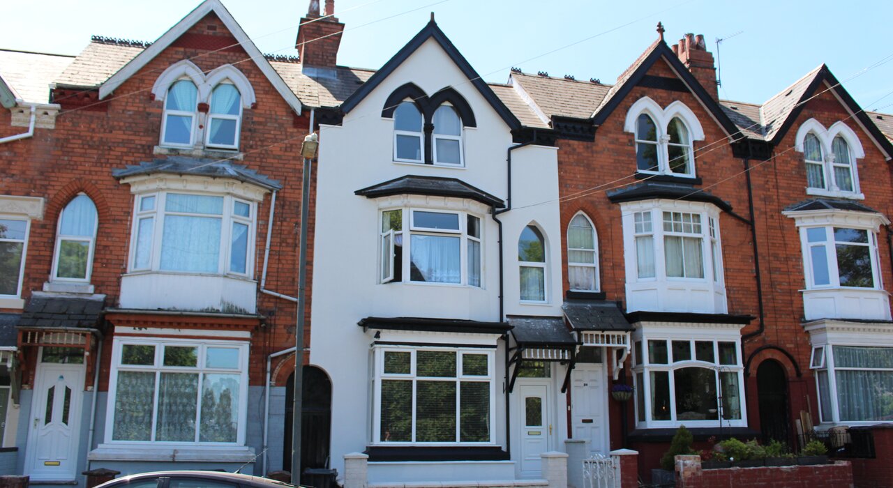 This image shows a row of terraced houses, with the middle property featuring a bright, newly insulated and rendered exterior. This highlights the use of external wall insulation (EWI) to improve energy efficiency, modernise the appearance, and enhance thermal comfort in older brick buildings.