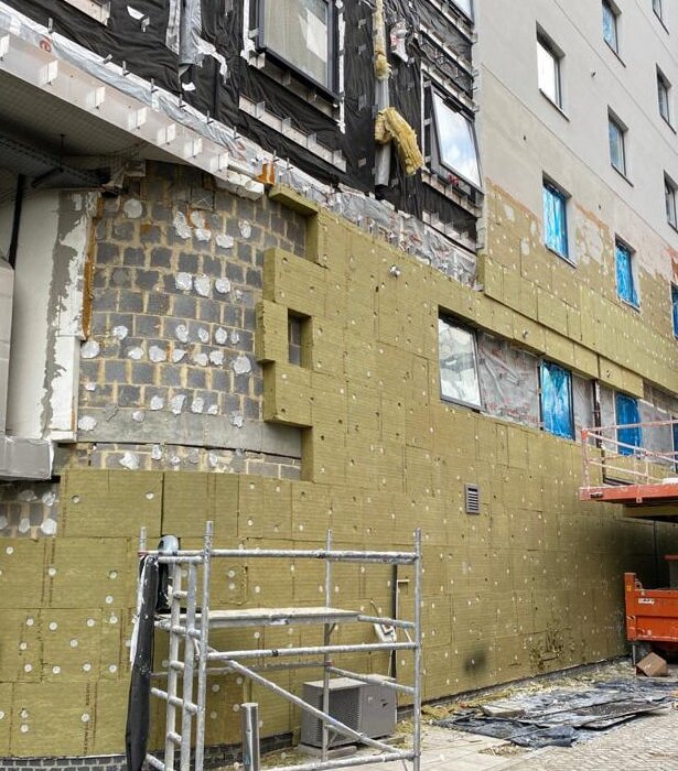 External wall insulation boards being installed on a commercial building. The mineral wool panels are fixed directly to the substrate, ready to be covered by mesh, basecoat, and render. This setup boosts thermal performance, reduces energy loss, and enhances the external appearance of the structure. Ideal for both refurbishment and new-build projects.