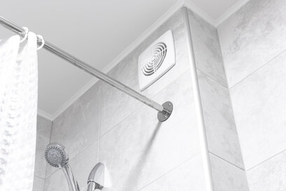 Modern bathroom ventilation fan installed above a tiled shower area, promoting better indoor air quality by reducing moisture and preventing mould—essential for maintaining healthy environments in well-insulated homes supported by EWI Store’s external wall insulation and rendering solutions.