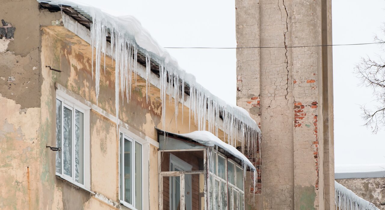 Old building with visibly damaged exterior walls and large icicles hanging from the roof—indicating poor insulation and heat loss. The cracked façade and water stains show the effects of thermal bridging and weather exposure. EWI Store provides external wall insulation and rendering systems that prevent such issues by improving energy efficiency and protecting building envelopes.