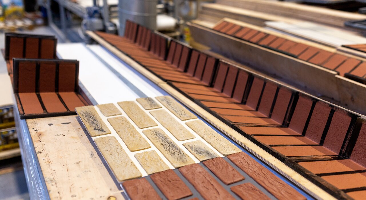 Close-up of brick slip cladding panels during the manufacturing or preparation stage. The panels consist of pre-bonded brick slips mounted on backing boards, allowing for quick and efficient installation on external wall insulation systems. This is a popular solution for achieving a traditional brick finish with modern thermal performance. EWI Store supplies brick slip systems and adhesives ideal for both refurbishment and new-build applications
