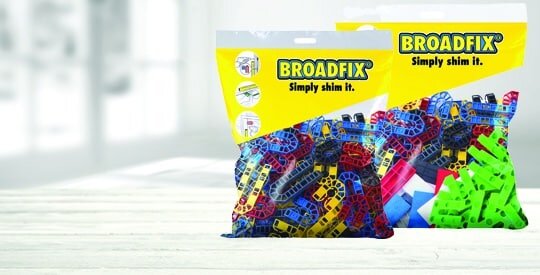 A package of BROADFIX shims displayed on a light wooden surface, showcasing their bright, multi-coloured plastic spacers used for leveling and alignment in construction projects—an ideal accessory when installing external wall insulation systems for precise application.