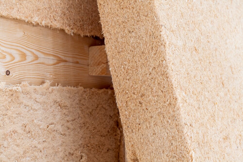 Close-up of natural wood fiber insulation panels fitted between timber frames in a wall, used for eco-friendly thermal and acoustic insulation in sustainable construction.