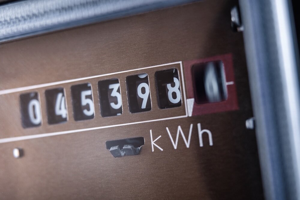 The image shows a close-up of an electricity meter displaying energy usage in kilowatt-hours kWh, with the reading showing 045398.