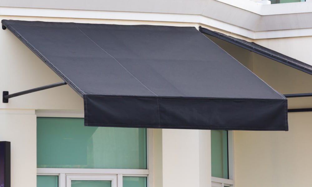 A black exterior awning provides shade over a window. While it helps with heat control, combining it with external wall insulation delivers greater energy savings.