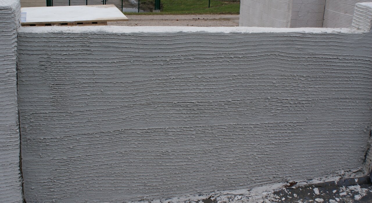  A grey 3D-printed concrete wall is visible, hinting at innovative construction methods. External wall insulation can be adapted to modern building techniques like 3D printing