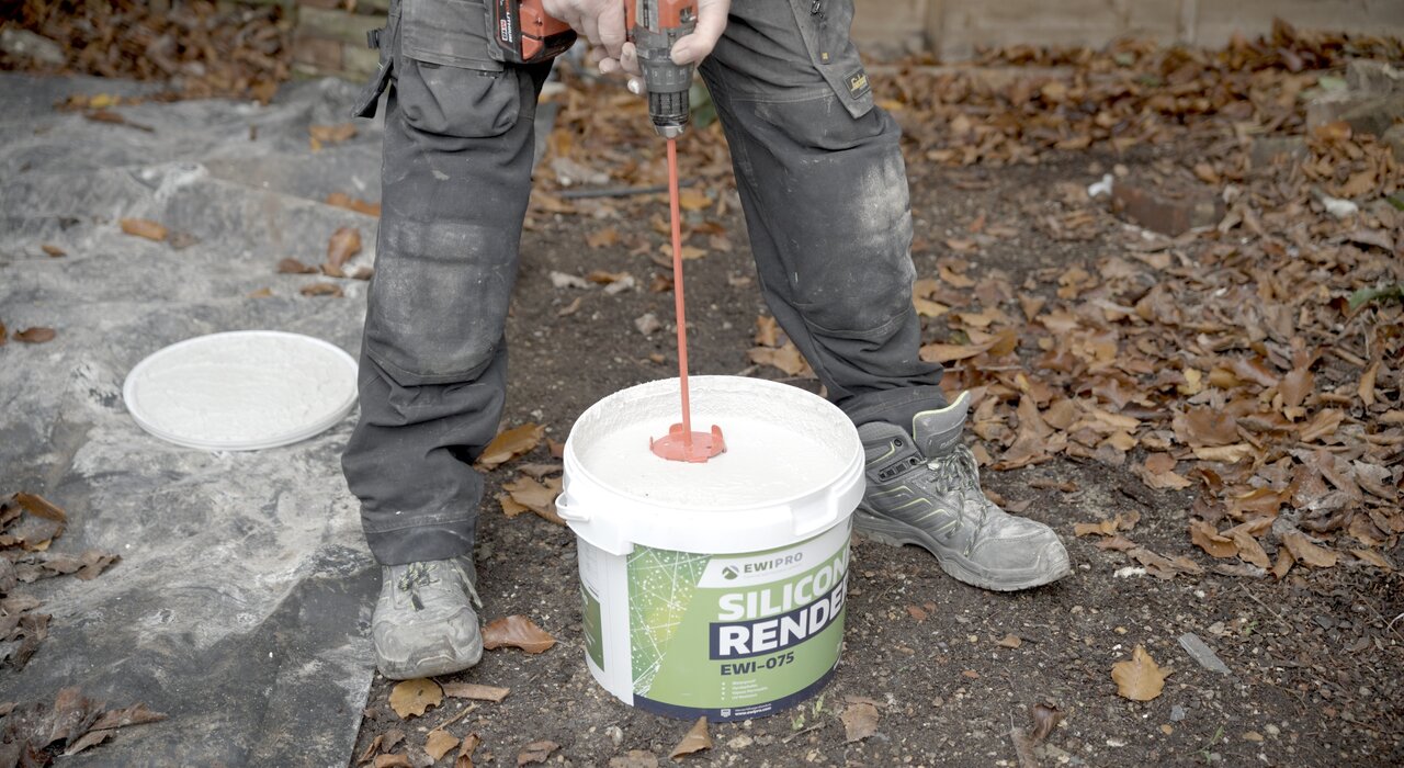 A worker is mixing silicone render with a paddle mixer. This type of render is flexible and breathable, ideal for use on external insulation systems.