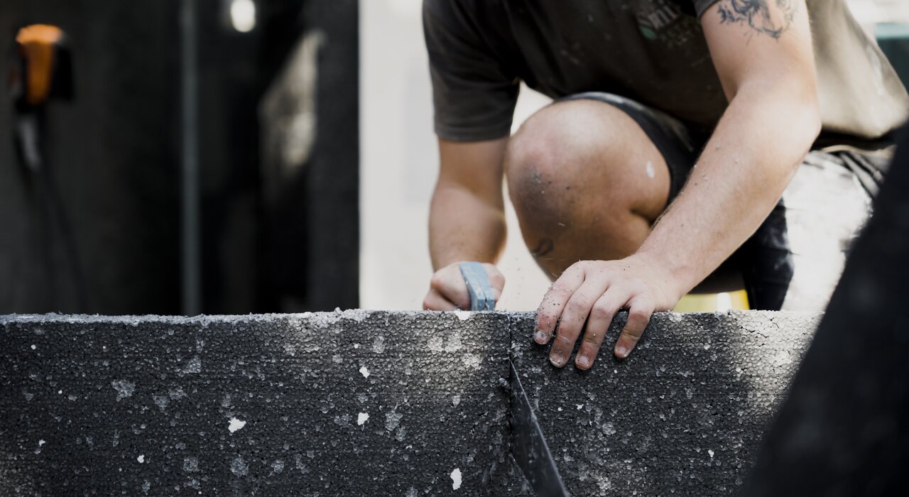 This shows a worker cutting insulation board with a hand saw. Precision is important to ensure a snug fit and avoid thermal bridges.