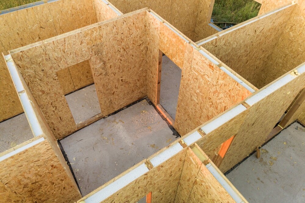 This image shows a timber-framed modular structure under construction, using structural insulated panels (SIPs). These panels combine oriented strand board (OSB) with built-in insulation, and are often paired with external wall insulation to further improve thermal efficiency and airtightness. Adding EWI on top of SIPs helps minimise heat loss and boosts energy performance in modern builds