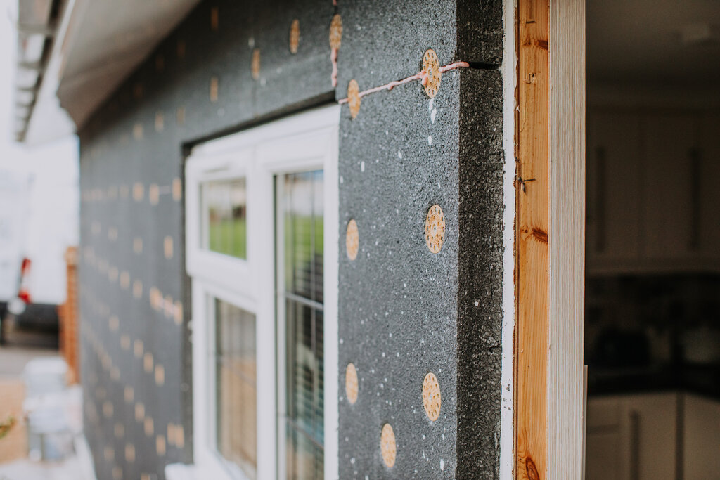 This image shows insulation boards attached around a window. It represents a crucial stage in applying external wall insulation, ensuring no thermal bridges.