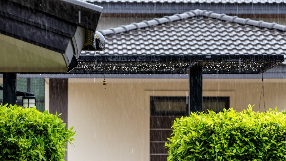 Rain pours from a roof overhang. Proper external wall insulation helps protect buildings from moisture and keeps interiors dry and warm.