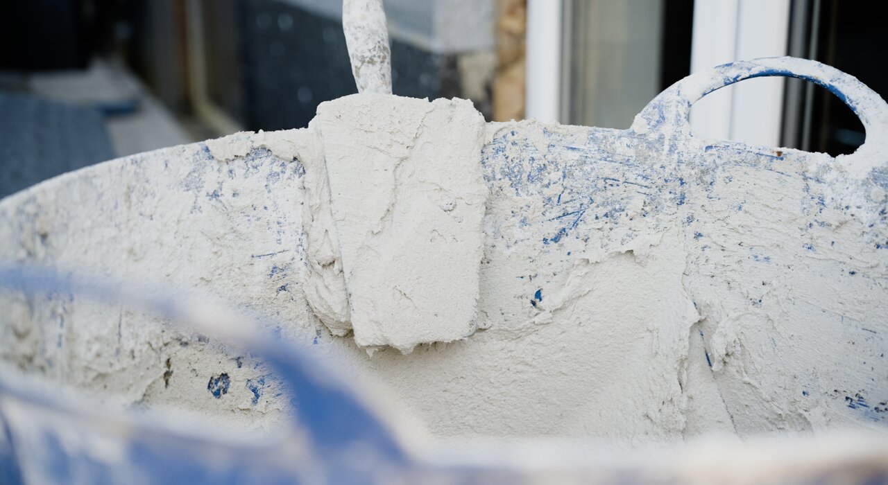 A bucket filled with render material, which is often applied over insulation boards as part of the external wall insulation finish system.