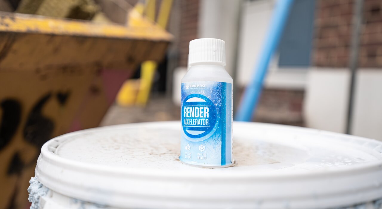 A bottle of EWI Pro Render Accelerator placed on a render tub, used to speed up drying times during cold or damp conditions. Additives like this are essential for winter working and are part of EWI Store’s render accessories range.