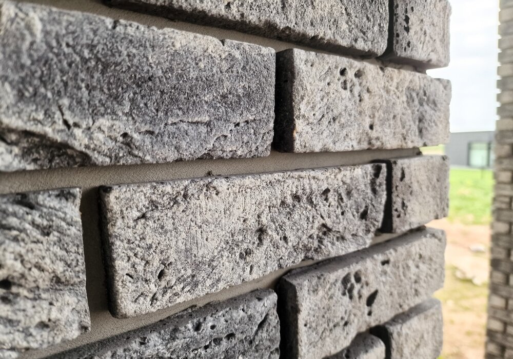 Close-up of a textured brick façade showcasing light grey bricks with rough, porous surfaces and clean mortar joints. This type of decorative brick slip finish adds a traditional yet contemporary aesthetic to exterior walls. Available from EWI Store, our brick slips offer durability, weather resistance, and authentic visual appeal ideal for modern retrofit and new build projects.