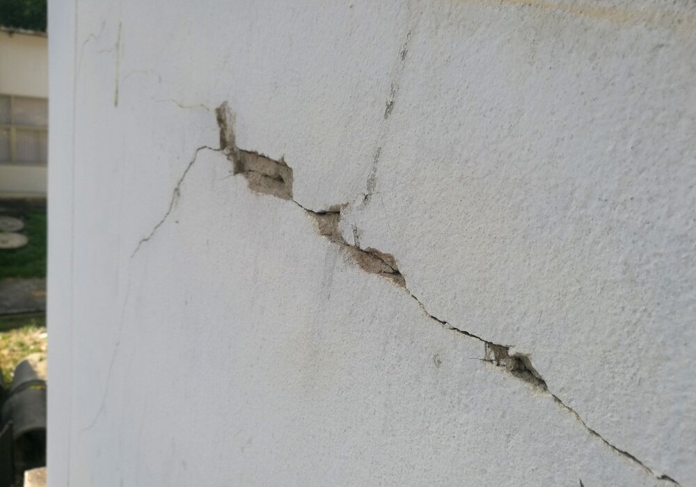 Close-up of a large crack in a rendered wall, exposing the underlying substrate. This type of damage is often caused by substrate movement or poor installation. EWI Store provides high-performance reinforcement mesh and basecoat solutions to prevent cracking and extend façade life.