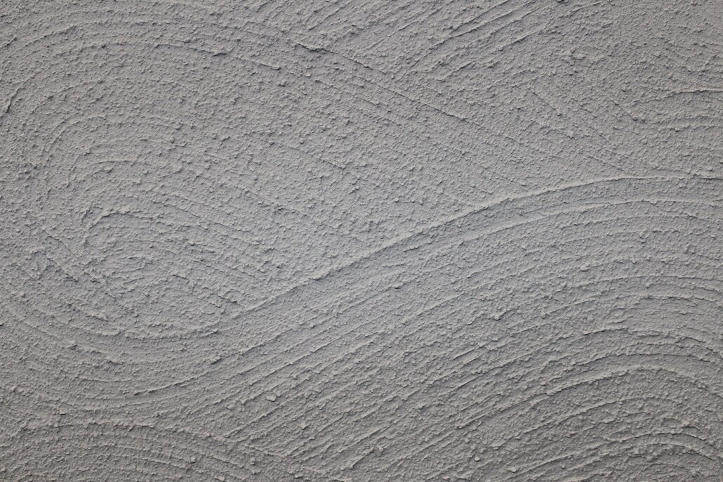 Close-up texture of a finished render surface with a distinctive swirl pattern. Decorative renders from EWI Store, such as Silicone Render (EWI-075), provide long-lasting protection with customisable textures and colours to enhance your façade’s appearance.