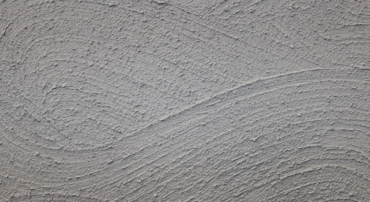 Close-up texture of a finished render surface with a distinctive swirl pattern. Decorative renders from EWI Store, such as Silicone Render (EWI-075), provide long-lasting protection with customisable textures and colours to enhance your façade’s appearance.
