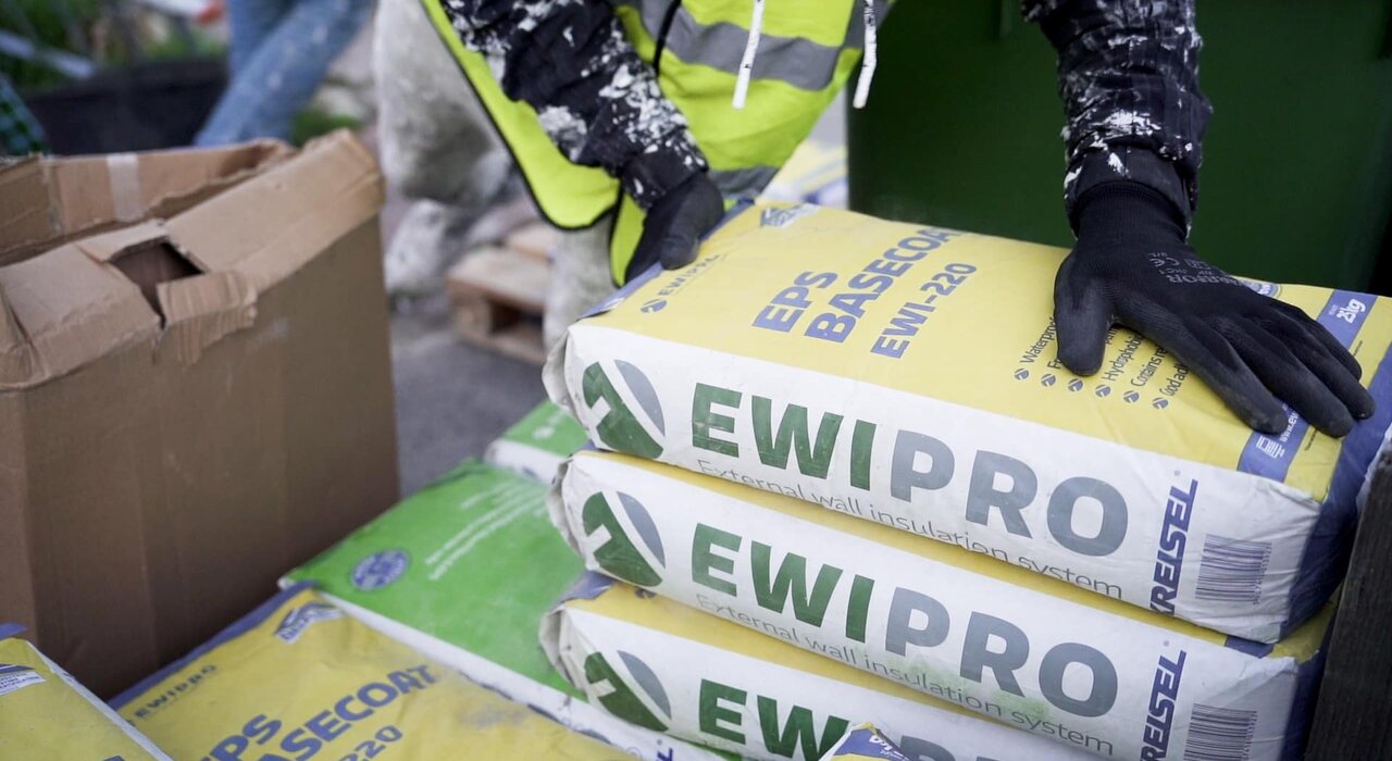 A worker handling bags of EWI Pro EPS Basecoat (EWI-220) on-site. Designed specifically for use in external wall insulation systems, EPS Basecoat provides strong adhesion and flexibility. Available from EWI Store, this basecoat ensures a smooth and secure base layer for EPS boards.
