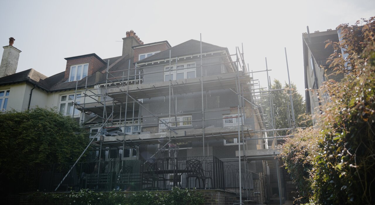 A large residential building covered in scaffolding, indicating ongoing external wall insulation or rendering work. Scaffolding allows safe access to upper levels during installation of insulation systems. EWI Store supplies all necessary components for high-quality façade renovations.