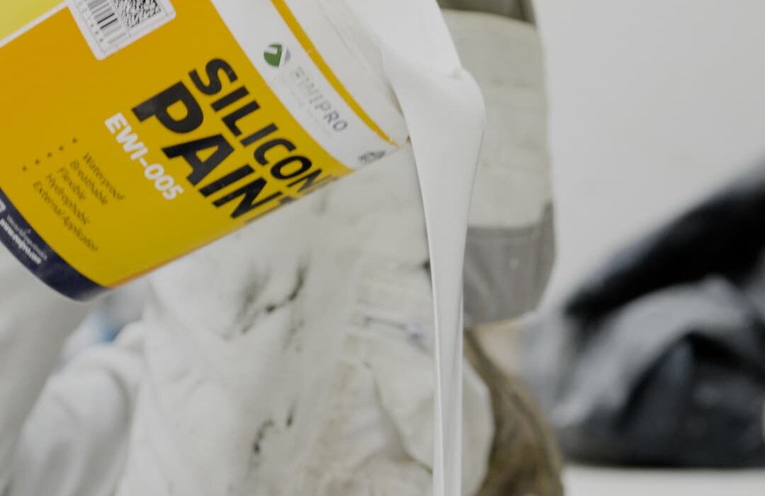 Close-up of a worker pouring EWI Pro Silicone Paint (EWI-005) into a roller tray. This premium-grade silicone paint is waterproof, breathable, flexible, and hydrophobic—ideal for external applications. Available from EWI Store, Silicone Paint offers long-lasting protection and a clean, modern finish for rendered surfaces.