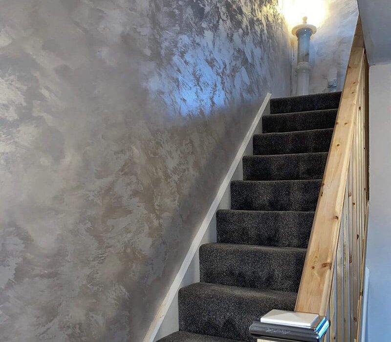 Close-up of a feature wall finished with polished plaster in a metallic bronze tone. The smooth, reflective surface adds a luxury finish ideal for interior spaces. Decorative plaster systems available from EWI Store offer custom texture and sheen.