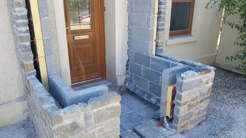 Construction site showing a partially built porch extension with cavity wall construction. Exposed insulation and internal blockwork demonstrate the step-by-step process of a properly insulated extension. EWI Store supplies cavity wall insulation systems for new builds and retrofits.