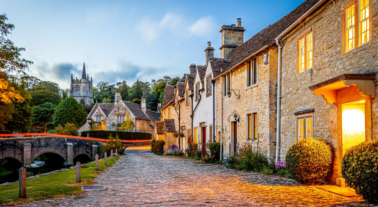 Charming street view of traditional stone cottages in a UK village at dusk. Featuring solid masonry walls and heritage render finishes, these buildings benefit from breathable solutions such as EWI Pro Lime Render (EWI-747), designed to preserve historical façades.