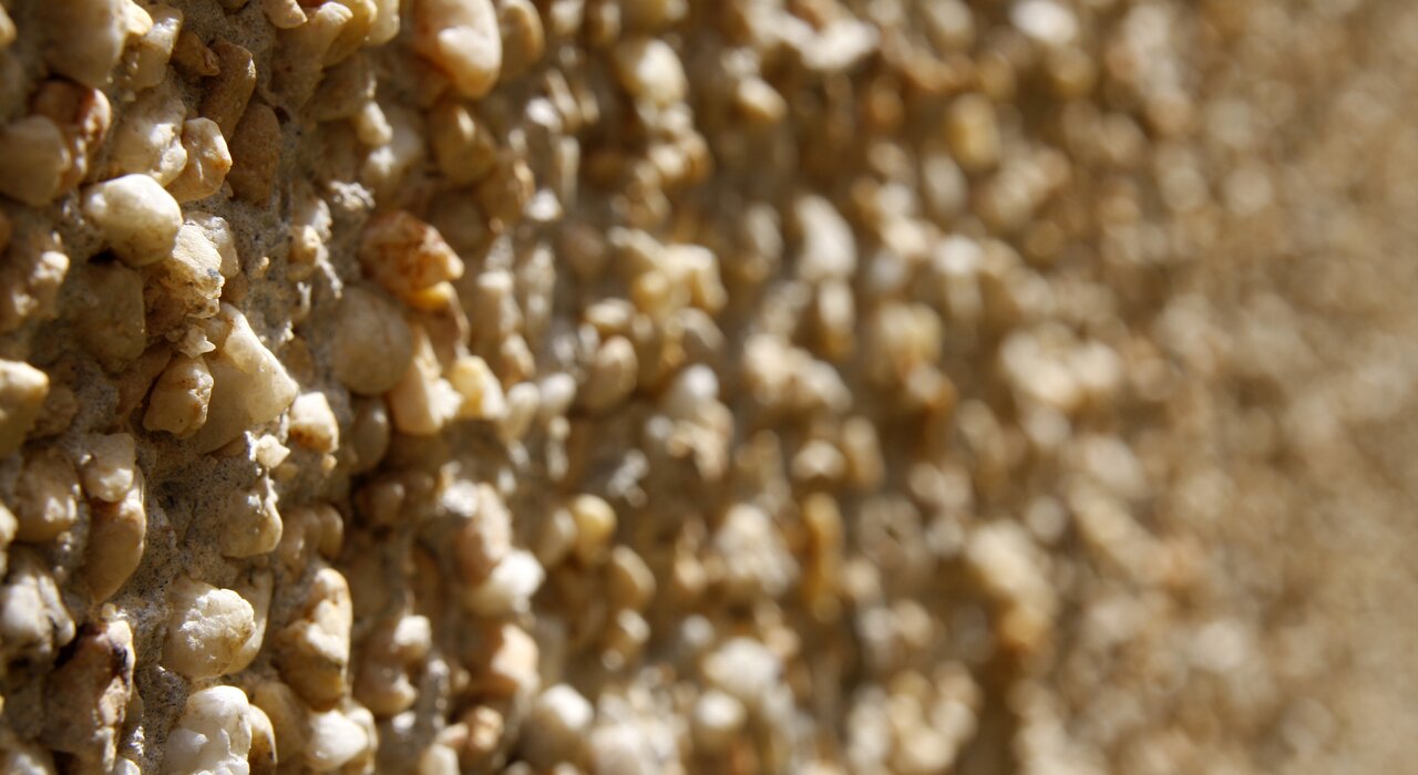 Close-up of a Pebbledash finish featuring decorative aggregate embedded in the surface. EWI Pro Pebbledash Render (EWI-065) creates a durable and weather-resistant facade, ideal for traditional homes seeking a low-maintenance textured finish. Available in a wide range of basecoat and dash aggregate options from EWI Store.