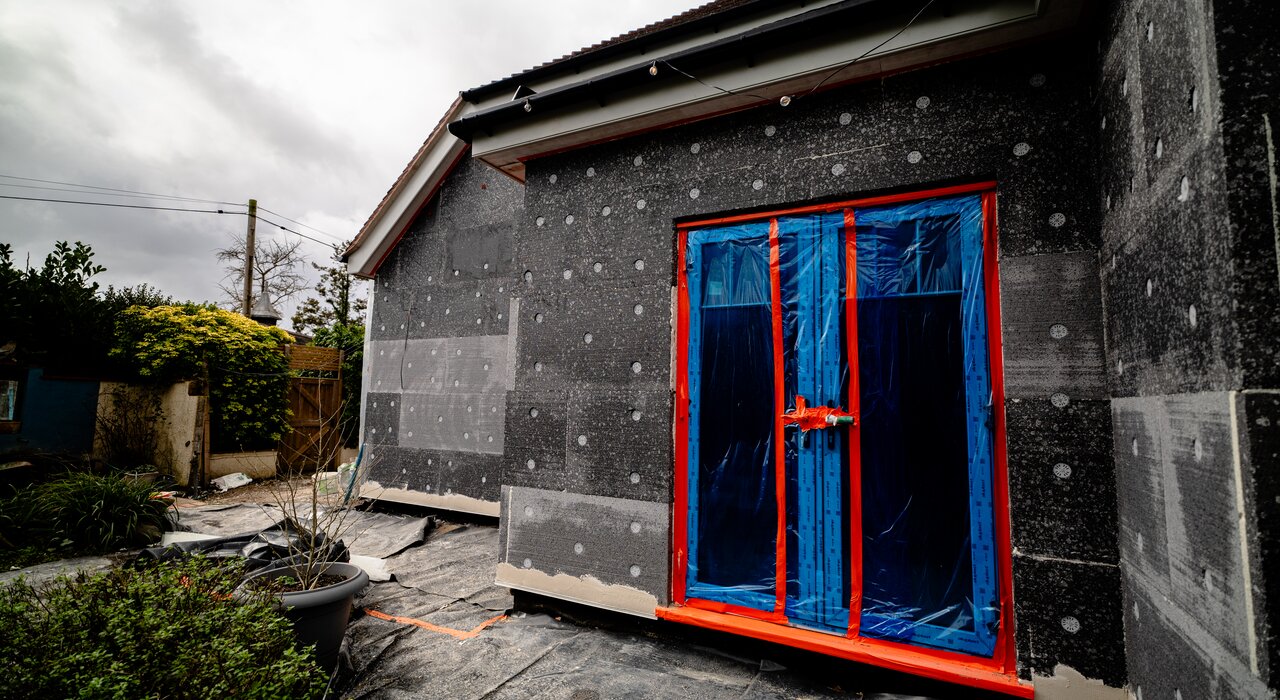 External wall insulation system being installed using EPS boards. The boards are mechanically fixed, and windows are protected with red tape and plastic sheeting. EPS systems from EWI Store offer excellent thermal performance and ease of installation.External wall insulated with mineral wool boards. The material’s fibrous structure enhances fire resistance and acoustic insulation. Available from EWI Store, this breathable solution is ideal for solid wall properties.