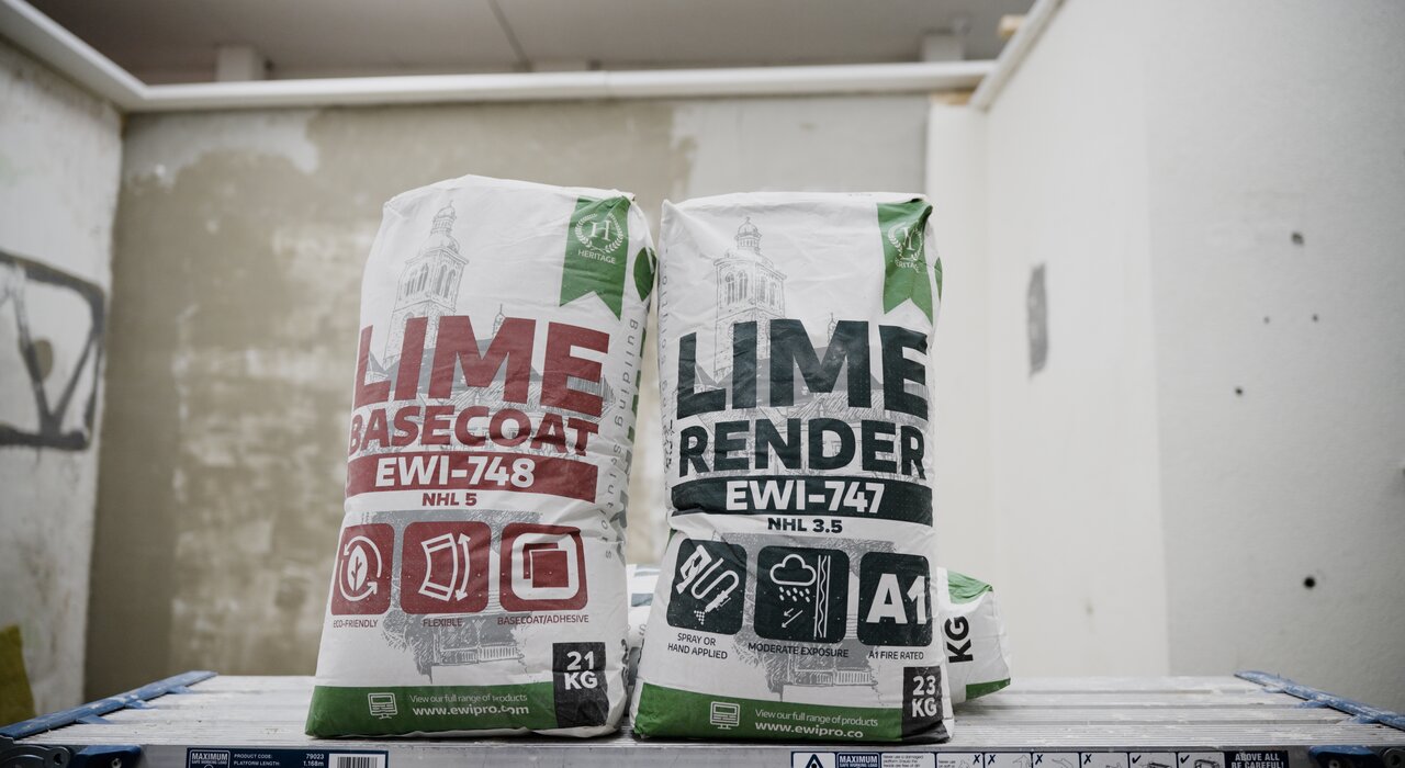 Bags of EWI Pro Lime Basecoat (EWI-748) and Lime Render (EWI-747) displayed on-site. These breathable, heritage-friendly solutions are ideal for use on solid wall properties, especially in conservation areas. Available at EWI Store, both products offer excellent adhesion, durability, and weather resistance for traditional substrates like stone and brick.
