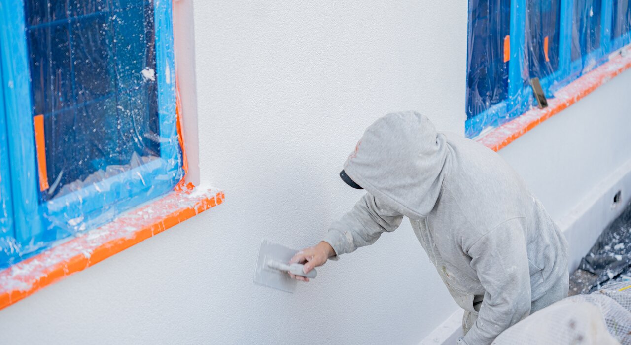 Installer applying a thin coat render to a protected wall. Available from EWI Store, our thin coat renders offer excellent durability, breathability, and weather resistance for a smooth, modern finish.