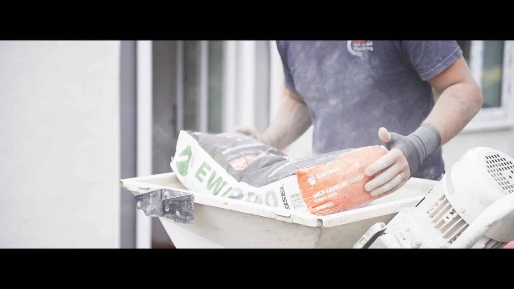 Worker loading EWI Pro and Strikolith materials into a render spraying machine. EWI Store supplies top-performing products for both hand and machine application, streamlining external wall insulation installations.