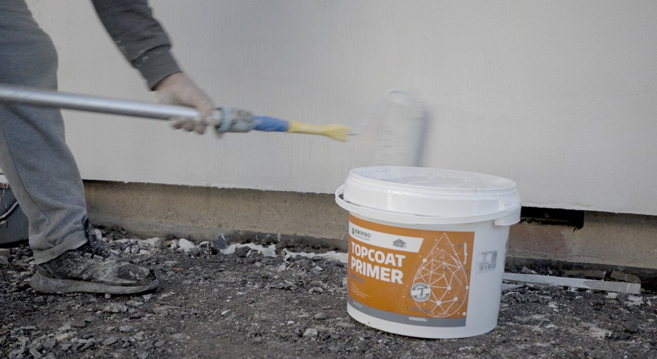 Worker applying EWI Pro Topcoat Primer with a roller. This high-performance primer enhances adhesion and ensures uniform absorption before applying silicone or acrylic renders. Available from EWI Store, Topcoat Primer is a crucial step in delivering a long-lasting, professional finish.