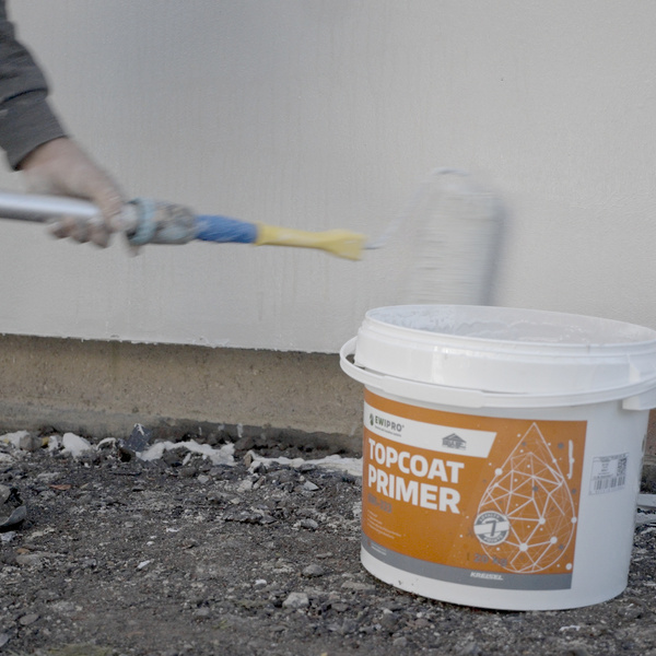 Worker applying EWI Pro Topcoat Primer with a roller. This high-performance primer enhances adhesion and ensures uniform absorption before applying silicone or acrylic renders. Available from EWI Store, Topcoat Primer is a crucial step in delivering a long-lasting, professional finish.