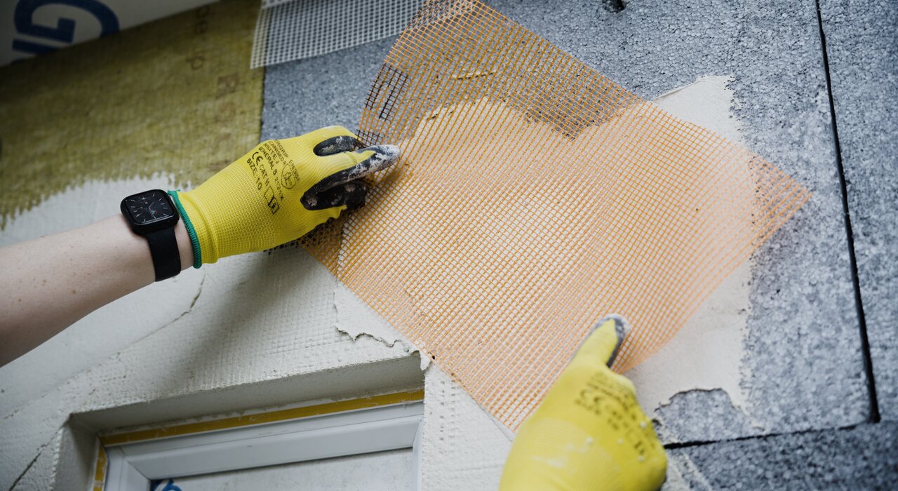 Close-up of a worker applying mesh reinforcement over basecoat on an EPS insulation board. Mesh enhances crack resistance and system durability. Available from EWI Store, our mesh solutions are designed to work seamlessly with our full range of EWI systems.