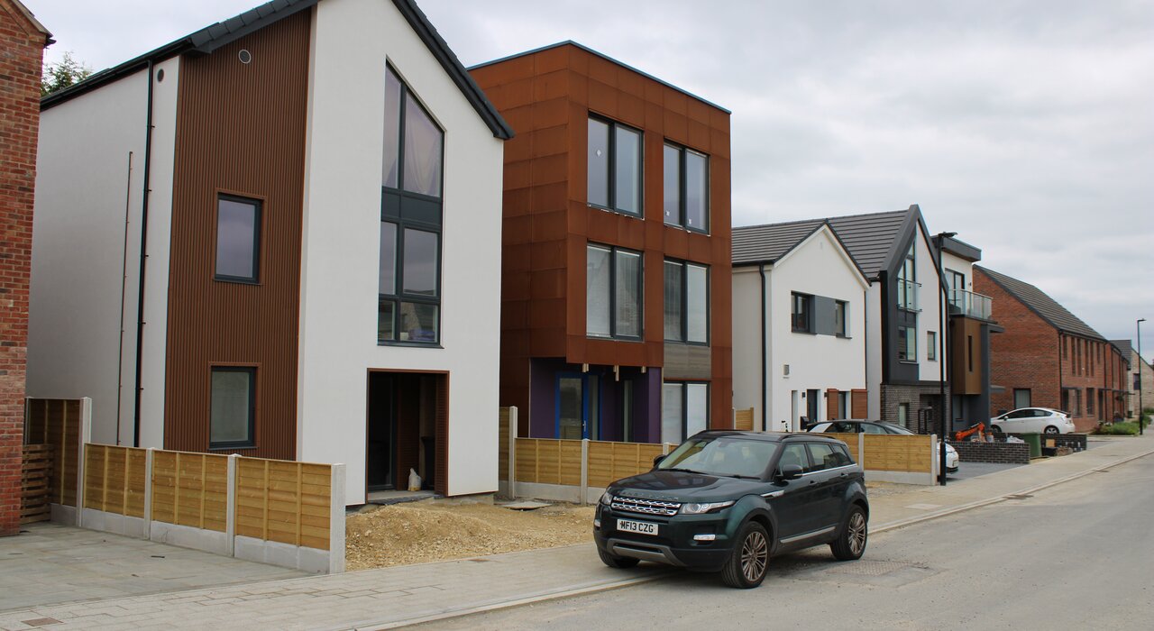 Street view of modern new-build homes featuring a variety of façade finishes, including silicone render. These energy-efficient homes demonstrate the visual appeal and thermal performance achievable with external wall insulation. EWI Store supplies a full range of EWI systems to suit contemporary architectural designs.