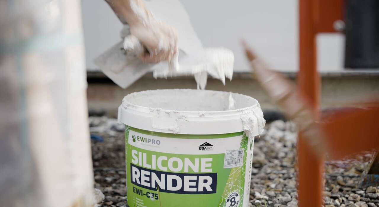Close-up of EWI Pro Silicone Render (EWI-075) being scooped from a bucket during application. This highly breathable, water-repellent render offers exceptional flexibility and crack resistance, making it ideal for external wall insulation systems. Available now from EWI Store.