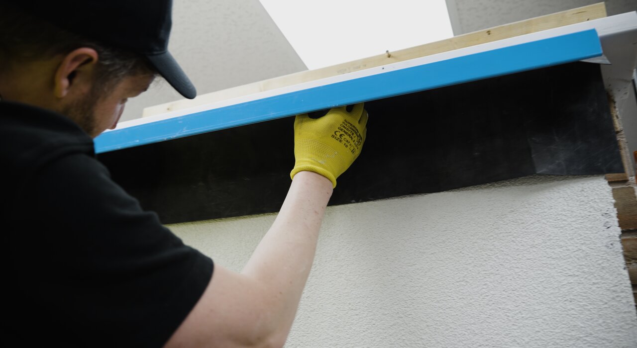 Installer fitting an EWI Pro Verge Trim above a window, ensuring water is directed away from the facade. Available from EWI Store, our range of verge and corner profiles ensures durability and precision in every EWI installation.