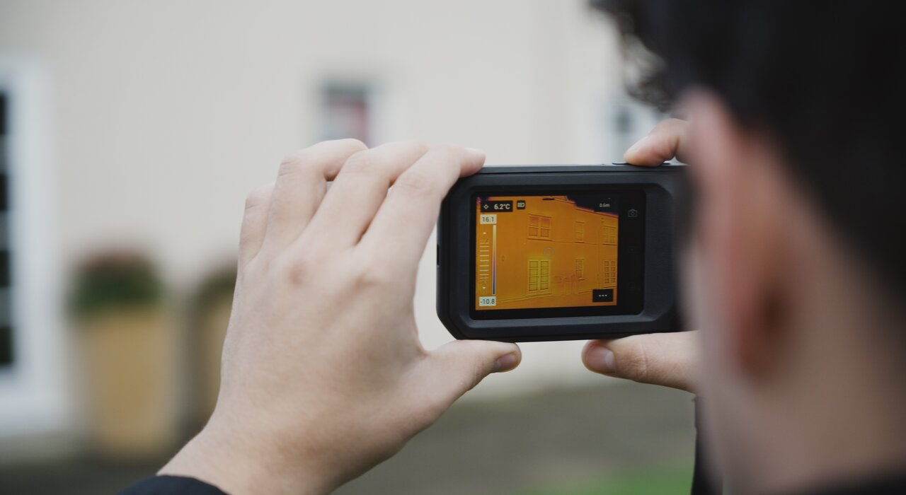Close-up of a thermal imaging camera in use, detecting heat loss through a building’s exterior. To minimise thermal bridging and improve overall insulation performance, EWI Store provides a full range of high-quality EWI systems including EPS, Mineral Wool and XPS, trusted by professionals across the UK.