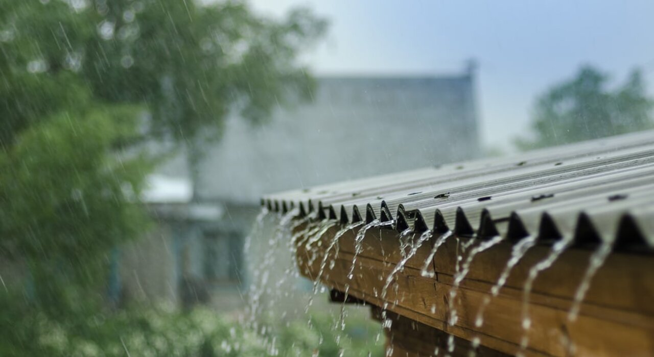 Rainwater running off a corrugated roof during a storm, highlighting the importance of effective weatherproofing. EWI Store supplies breathable yet waterproof render systems designed to shield homes from harsh UK weather while maintaining optimal moisture balance in the wall structure.