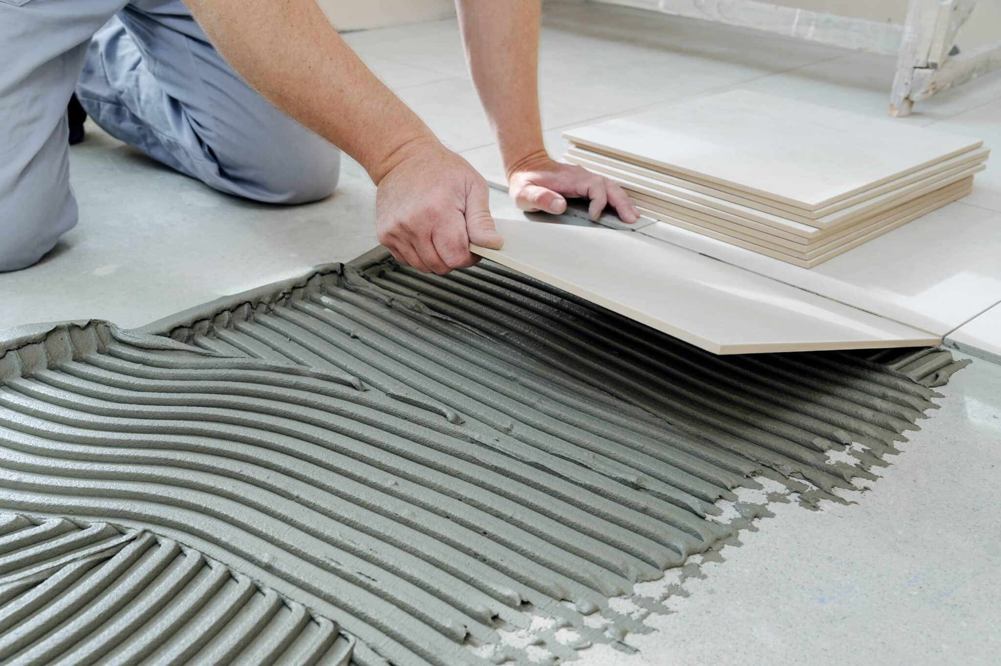 a tile being laid down onto adhesive that is levelling the surface